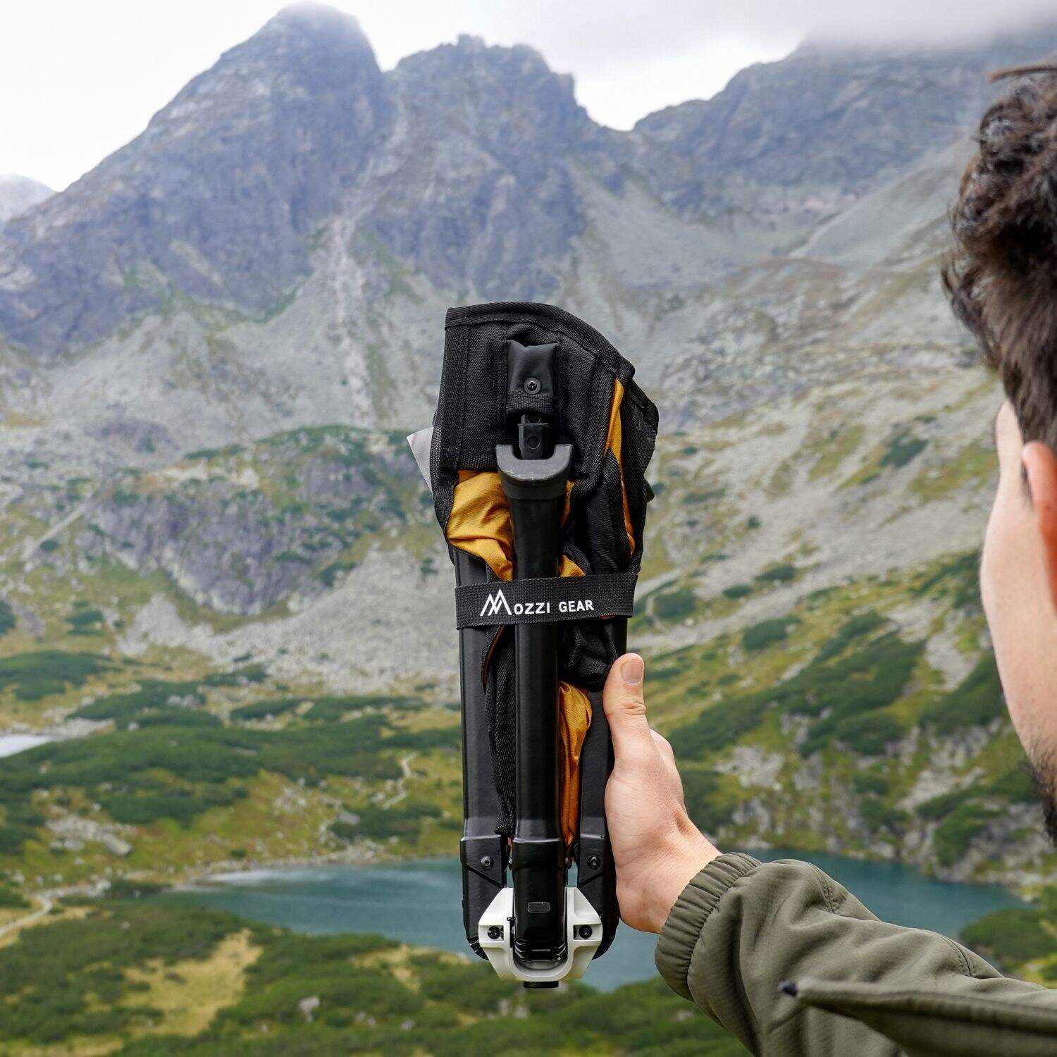 Person holding a Ozzi Outdoor Chair with a mountainous landscape in the background