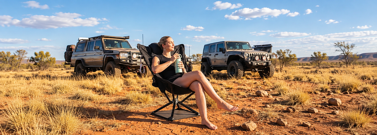 Woman relaxing in a portable outdoor lounge chair beside off-road vehicles.
