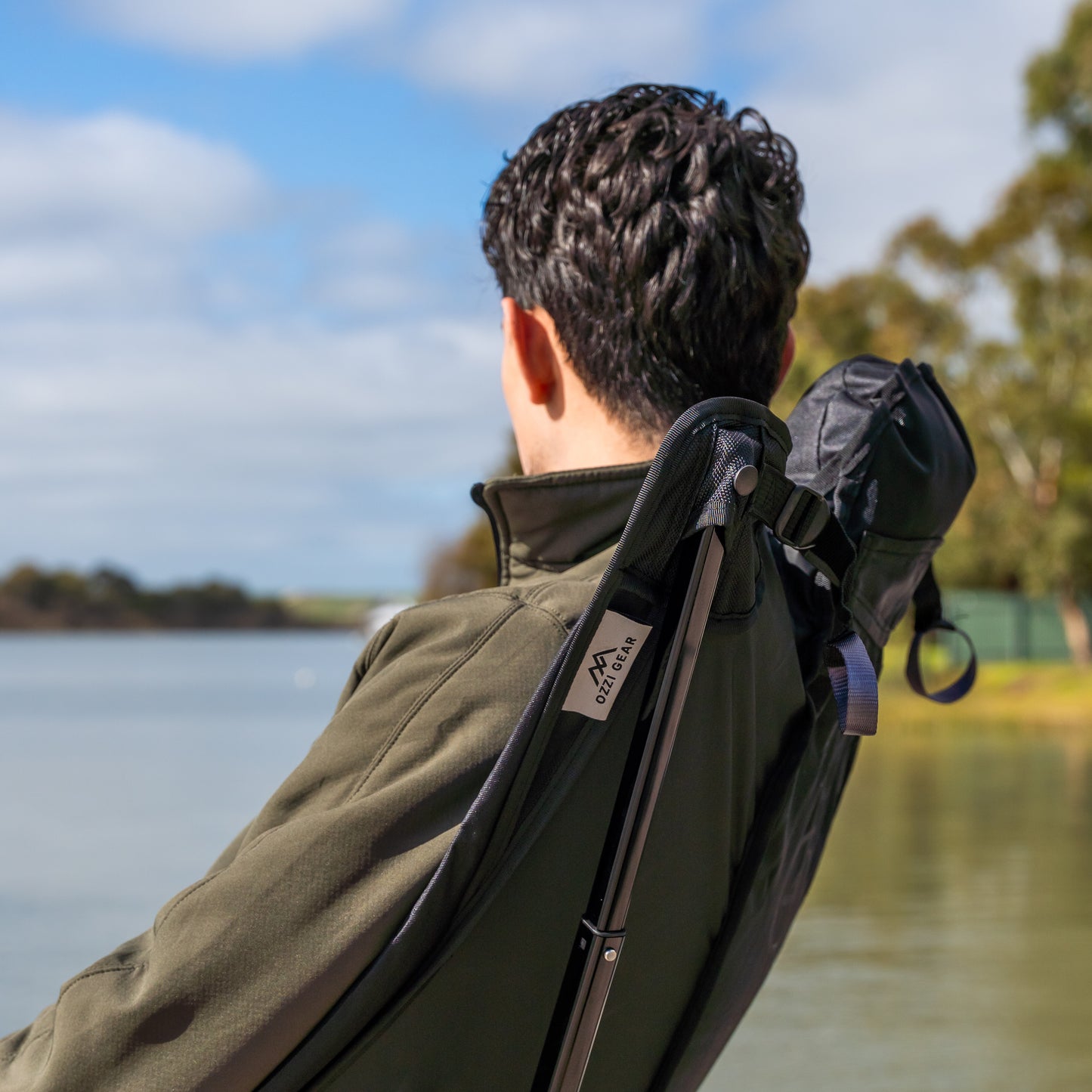 Person sitting on Ozzi Gear Lounger next to lake