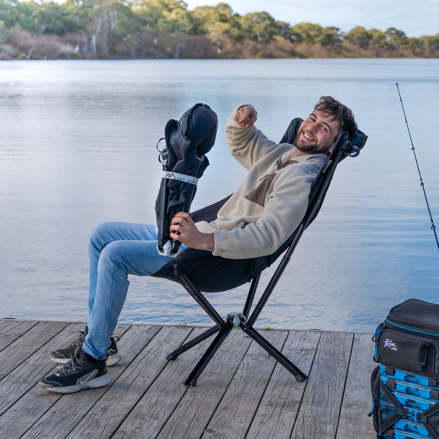 Man sitting on the foldable, compact Ozzi Gear lounger by a lake